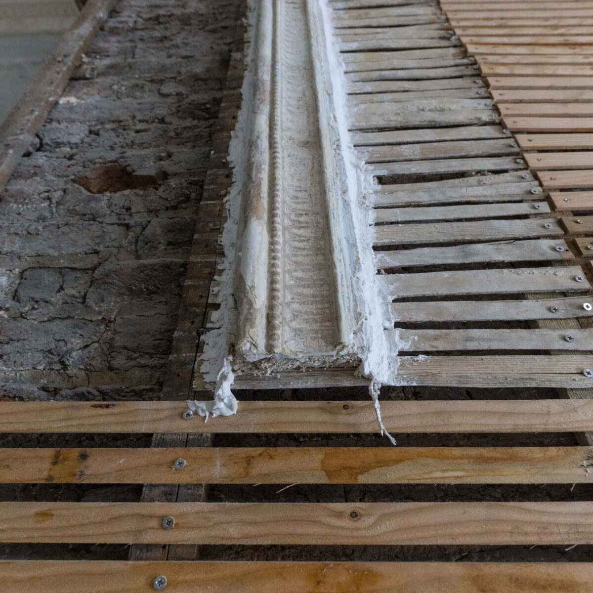 Close-up of a newly installed timber lath wall at the Arding and Hobbs building in London, prepared for traditional lime plaster application. The image highlights material contrasts on site, illustrating the integration of new heritage-appropriate substrates alongside retained historic fabric. Ideal reference for architects focused on compatible materials and breathable construction in conservation projects.