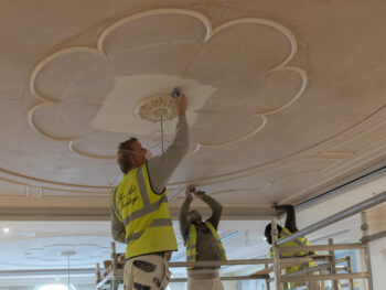 Artisans installing bespoke plaster ceiling rose and decorative mouldings in a new luxury residence