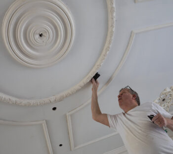 Craftsman adding an ornate plaster ceiling rose in a period property interior