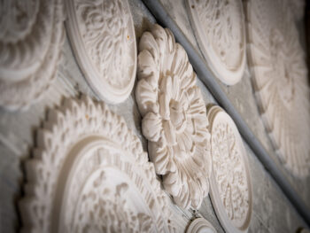 Collection of ornate plaster ceiling roses from historic designs displayed on workshop wall